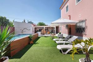 a backyard with a pool and chairs and an umbrella at J R Dream house in Quarteira