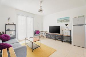 a living room with a couch and a tv at Le Saint Martin Duplexe à la Mer in Bréhal