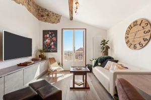 a living room with a couch and a clock on the wall at Maison de ville Fréjus in Fréjus