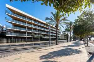 a building with palm trees in front of a sidewalk at Apartamento Ballena in Cambrils