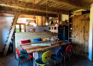 a kitchen with a wooden table and colorful chairs at Chalet Panorama Res Albert in San Guglielmo
