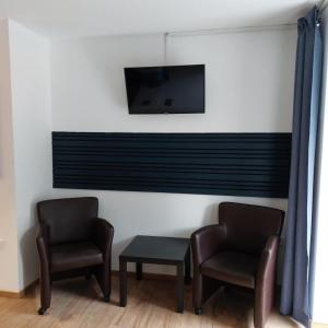 two chairs and a table and a tv on a wall at Haus Moselliebe Komfortzimmer in Ediger-Eller