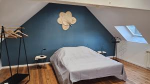 a bedroom with a blue wall with a bed and two tables at gite in Saint-Vaast-la-Hougue