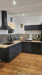 a kitchen with black cabinets and a wooden floor at gite in Saint-Vaast-la-Hougue