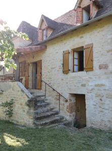 an old stone house with stairs and wooden doors at Maison Quercynoise in Corn