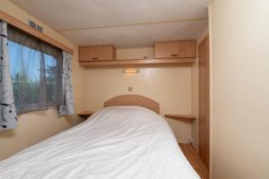a bed in a small room with a window at Mobilhome kervoyal 56 in Damgan