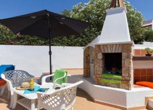 a patio with a fireplace and an umbrella at Casa Dos Mas in Cala en Porter