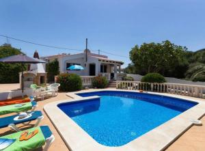 a swimming pool with chairs and a house at Casa Dos Mas in Cala en Porter