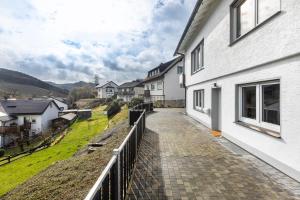 a balcony of a white house with a walkway at Ferienwohnung Esselsteigblick in Eslohe