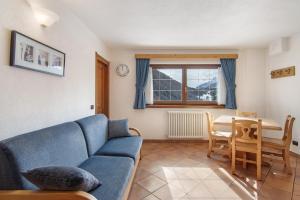 a living room with a blue couch and a table at Residence Larice Bianco App n5 in Campodolcino