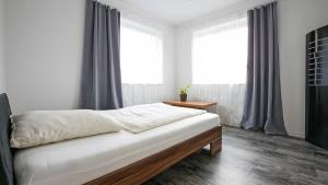 a bedroom with a bed with white sheets and windows at Apartment by Janzen -E- in Rheine