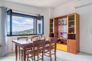 a dining room with a table and chairs and a large window at Casa Cuccureddu in Jerzu