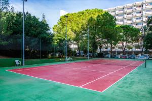 a tennis court with trees and a building in the background at Sweet Sea in Port d'Alcudia