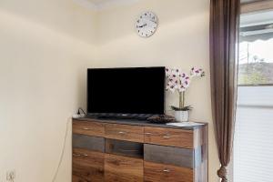 a flat screen tv on a wooden dresser with a clock at Ferienwohnung Ketterer in Hüfingen