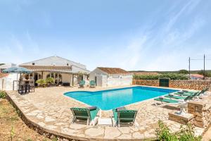 a swimming pool with chairs and a house at Finca Son Sanxo in Alaior