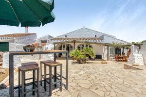 a stone patio with a table and stools in front of a house at Finca Son Sanxo in Alaior