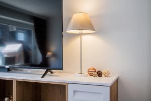 Eine Lampe steht auf einem Tisch neben einem Fernseher. in der Unterkunft Syltbrise 22 in Sylt
