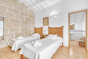 two beds in a room with a brick wall at Finca Son Sanxo in Alaior +19 photos