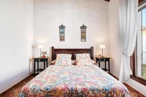 a bedroom with a bed with two tables and two windows at Villa Elsa in Conil de la Frontera +17 photos