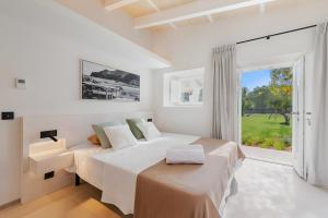 a white bedroom with a large bed and a window at Can Mas Villa Antigua in Pollença +37 photos