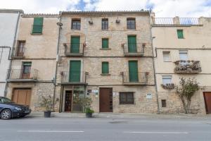 an old stone building with green doors and windows at Cal Menut in Belianes