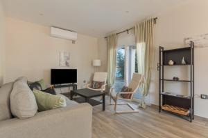 a living room with a couch and a tv at Euphoria Apartments in Lixouri