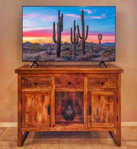 a television on top of a wooden cabinet with cactus at Spacious Desert Suite Minutes to Phoenix Fun - Pet Friendly! in Avondale