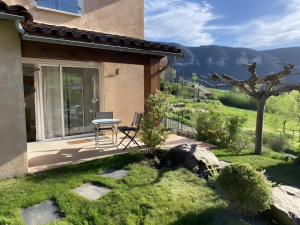 a patio of a house with a table in the grass at Gite Le Calcadis in Mostuéjouls