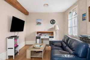 a living room with a leather couch and a tv at Gîte Du Centre avec terrasse in Romorantin