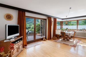 a living room with a television and a table with chairs at Haus Schindler in Ottenhöfen