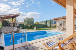 a swimming pool with two chairs next to a house at Villa M Vallon Pont d'arc in Vallon-Pont-dʼArc