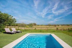 a swimming pool in the middle of a lawn with two chairs at Es Camp Pla in Sineu