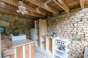 a kitchen with a stove and a stone wall at Tente Glamping Éco-Chic in Auriac-du-Périgord +18 photos