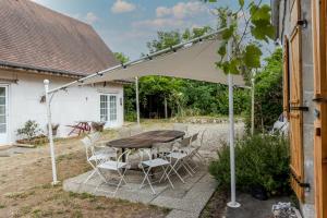 a patio with a table and chairs under an umbrella at Tente Glamping Éco-Chic in Auriac-du-Périgord