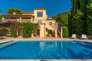 a villa with a swimming pool in front of a house at Finca Assindia, Costa de los Pinos in Son Servera