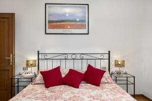a bedroom with a bed with red pillows and two lamps at Podere Sasso 3 in San Gimignano