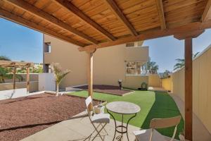 a patio with a table and chairs and a green lawn at Sandra La Perla in El Médano