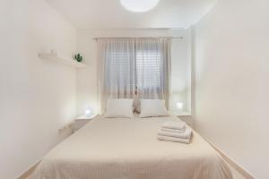 a white bedroom with a large bed with towels on it at Sandra La Perla in El Médano +21 photos