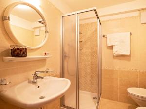 a bathroom with a sink and a shower with a mirror at Ciasa Lino Sas da le Undesc in Pozza di Fassa