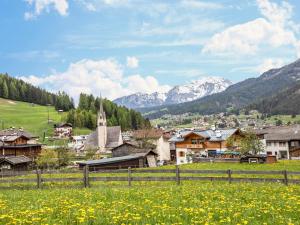 a village in the mountains with a field of flowers at Ciasa Lino Sas da le Undesc in Pozza di Fassa