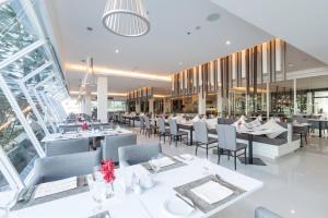 a restaurant with white tables and chairs and windows at Kantary Hotel And Serviced Apartment, Amata, Bangpakong in Ban Tamru +42 photos