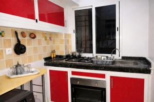 a kitchen with red and white cabinets and a sink at Spacious 2BR Apartment with Moroccan Salon near Aquaparc Tamaris Casablanca in Casablanca