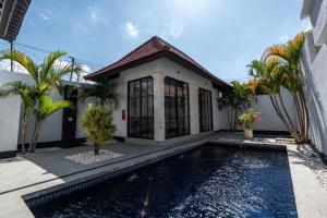 a house with a swimming pool in front of a house at Blue Marlin Villas Legian in Legian