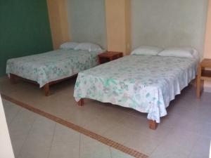 two beds in a room with two tables and sidx sidx sidx at Hotel Mecalco in Huazuntlán +5 photos