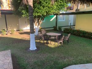 a table and chairs in a yard with a palm tree at Hotel Mecalco in Huazuntlán