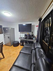 a living room with a black leather couch and a television at Departamento central Lg in Pereira