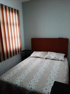 a bed in a bedroom with a window and a bedspread at Casona Feran in Pasto