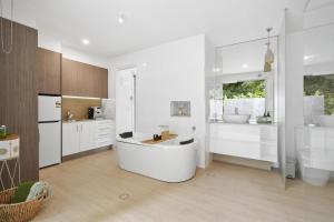 a white bathroom with a tub and a sink at Secluded rainforest getaway in Currumbin Valley +8 photos