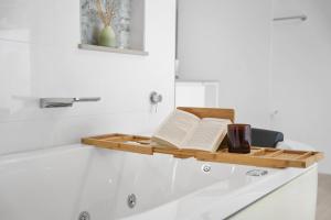 a wooden shelf with a book and a cup on a bath tub at Secluded rainforest getaway in Currumbin Valley