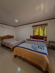 two beds in a bedroom with a window at Casa Osa Azul in Puerto Jiménez